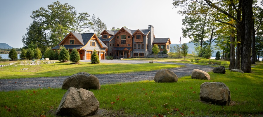 Natural stone veneer on a large home surrounded by trees and landscape stone